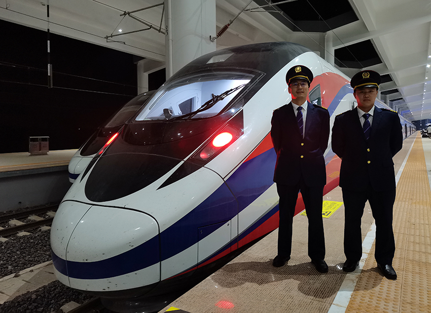 劉銀能（右一）與中國(guó)師父鄔俊鴻在動(dòng)車組前合影。受訪者供圖