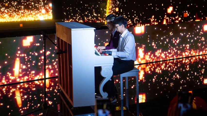 智能仿生手使用者古月與少年鋼琴家舒海峰合奏。主辦方供圖